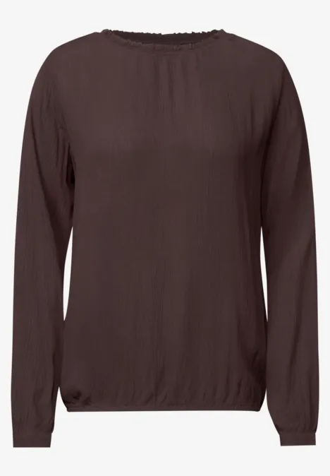 Blouse marron à manches longues et encolure ronde, coupe légèrement cintrée.