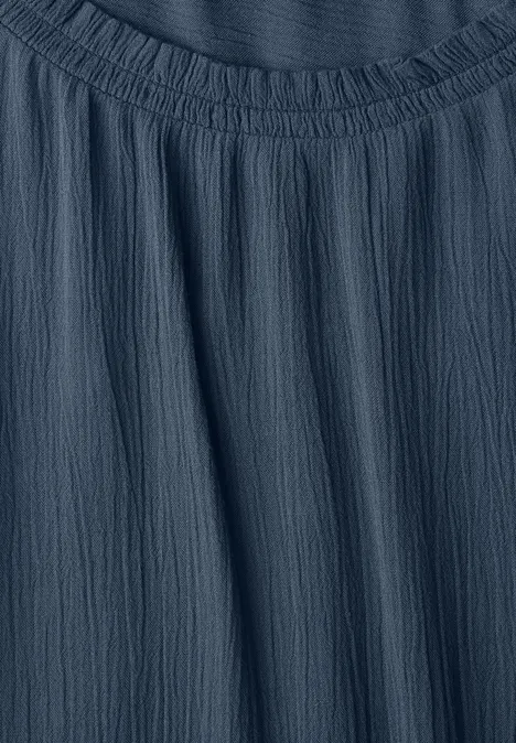 Blouse à manches longues et col rond avec détails smockés moonlight blue Gros plan sur un tissu bleu foncé froissé avec un col carré et un léger effet texturé.