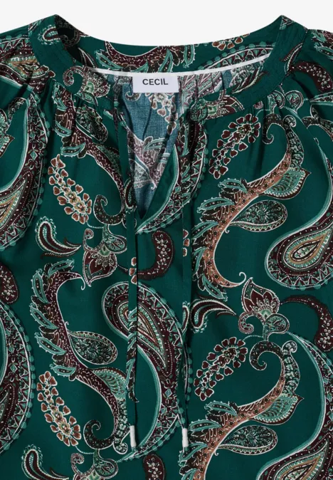 Grüne Bluse mit Paisley-Muster und Bindeband am Ausschnitt.