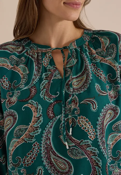 Grüne Bluse mit Paisley-Muster und bindbarem Schlüsselloch-Ausschnitt.