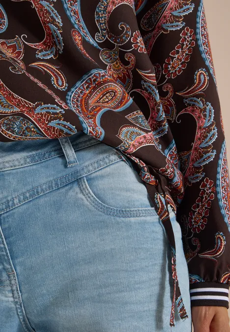 Lichtblauwe jeans en een bruin paisleyblouseje, aan de zijkant geknoopt.