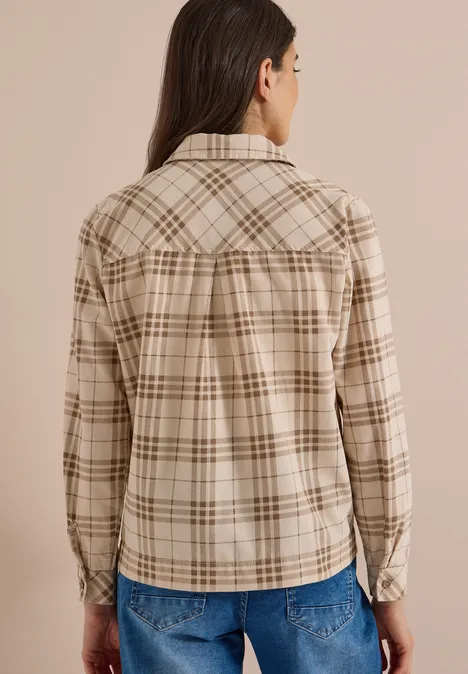 Rückansicht einer Person in einer beige-braun karierten Jacke und blauen Jeans.