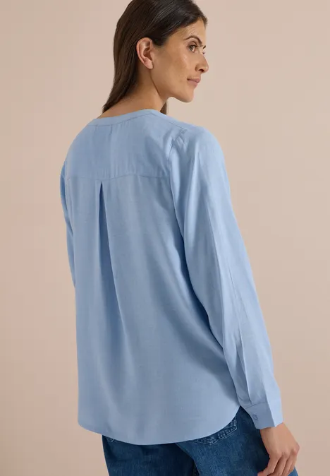 Langarm Tunika mit Split Neck und Tape blouse blue melange Frau von hinten in hellblauer Bluse und Jeans vor neutralem Hintergrund.