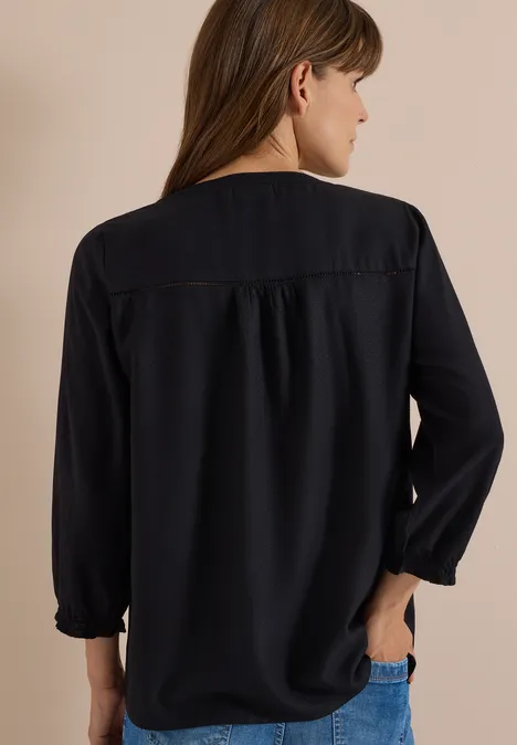 Frau von hinten in locker sitzender, langer dunkelblauer Bluse mit Gummibündchen.