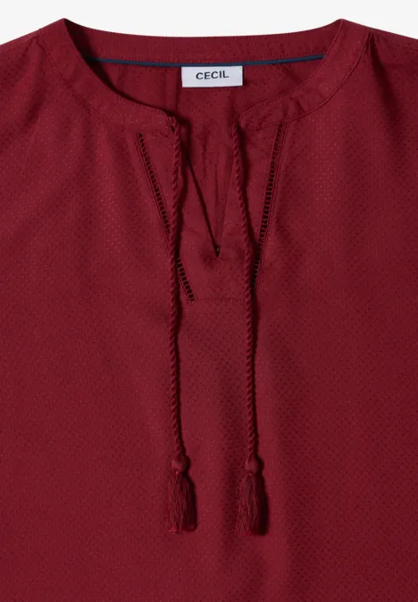 Rotes Langarm-Damenoberteil mit V-Ausschnitt, Quasten und feinem Punktmuster.