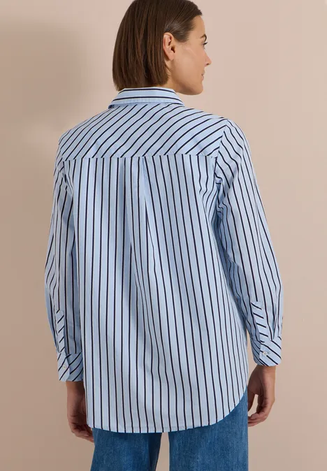 Chemisier long à rayures blouse blue Vue de dos d’une femme portant une chemise rayée bleu et blanc avec un jean, fond neutre.