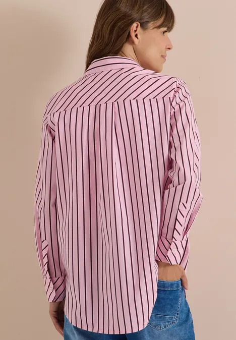 Chemisier long à rayures mellow rose Une personne vue de dos porte une chemise rose à rayures blanches et un jean.