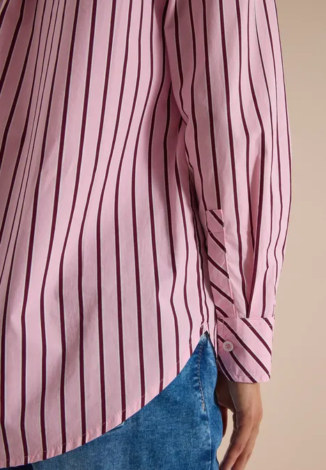 Chemisier long à rayures mellow rose Vue latérale d'une personne portant une chemise rose à rayures noires et un jean bleu