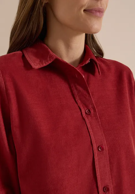 Chemisier à manches longues en velours côtelé russet red Gros plan d’une femme en chemise rouge à col et boutons.