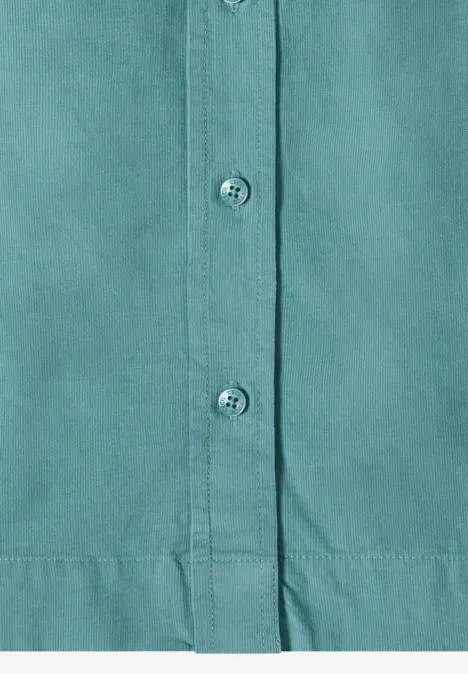 Chemisier à manches longues en velours côtelé mineral blue Gros plan sur une chemise turquoise à patte de boutonnage, trois boutons visibles et couture d'ourlet.
