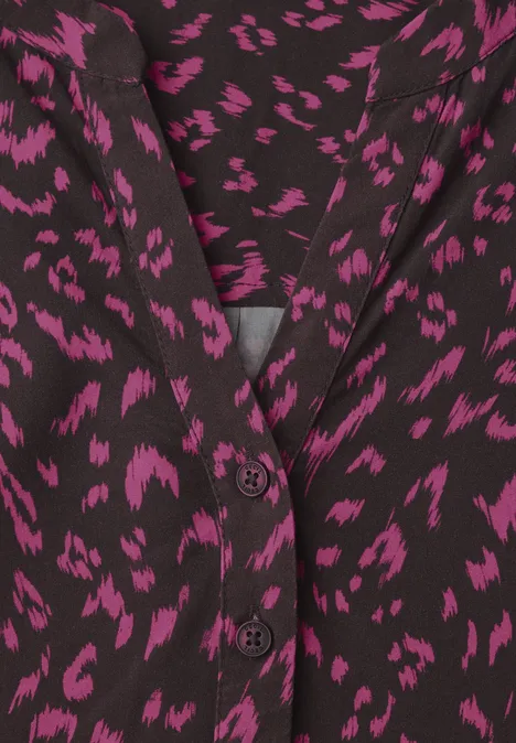 Schwarze Bluse mit unregelmäßigem pinken Leopardenmuster und V-Ausschnitt, zweireihige Knopfleiste.