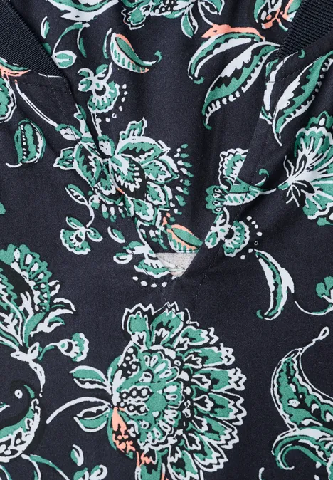 Chemisier à manches longues, à col fendu et imprimé urban dark blue Gros plan d’un tissu noir orné de fleurs stylisées vertes et blanches.