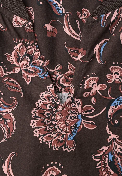 Nahaufnahme eines dunkelbraunen Blusenstoffs mit rosa-blauen Paisley- und Blumenmustern.