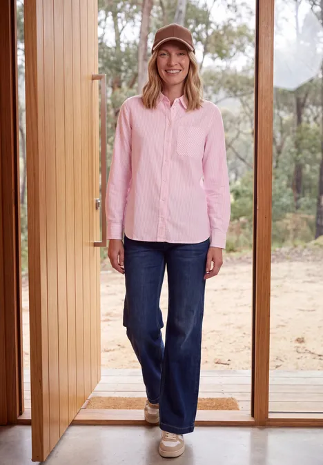 Langarm Hemdbluse mit Streifen mellow rose Eine lächelnde Frau in Jeans, rosa Hemd und Cap steht in geöffneter Tür vor waldiger Landschaft.