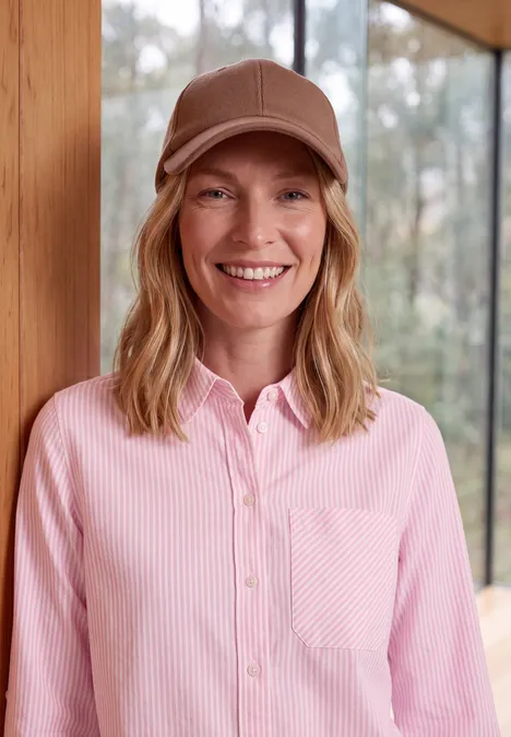 Langarm Hemdbluse mit Streifen mellow rose Eine lächelnde Frau in rosa Hemd und Baseballcap vor einem Fenster mit Holzzarge.