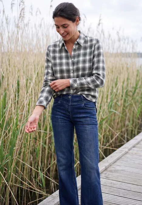 Langarm Flanell Bluse mit Karomuster vanilla white Frau in kariertem Hemd und Jeans steht lächelnd auf einem Steg zwischen Schilf.