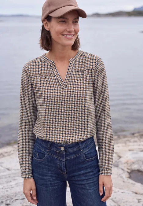 Langarm Tunika mit Split Neck und Print mocha brown Frau mit kariertem Hemd, Jeans und Baseballkappe steht lächelnd am Ufer.