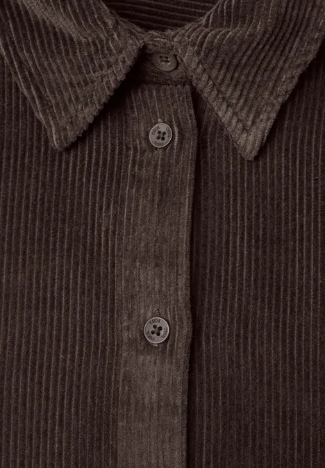 Nahaufnahme einer braunen Cordjacke mit sichtbarer Knopfleiste und Hemdkragen.