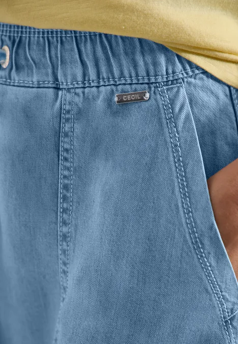 Blaue Jeans-ähnliche Hose mit Gummibund und Seitentasche, Teil eines gelben Oberteils.