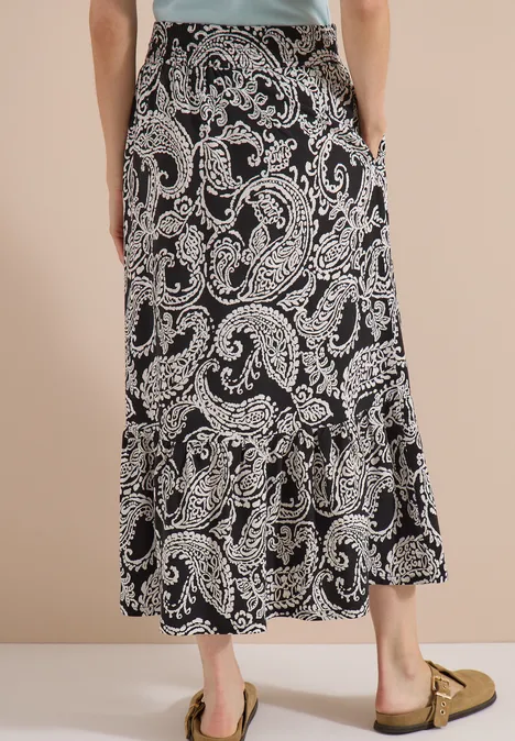 Schwarzer Maxirock mit beigem Paisley-Muster, locker fallend, hinten leicht gerafft.
