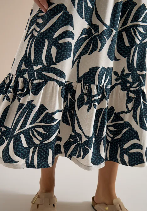 Maxi-Rock mit sommerlichem Blättermuster palm breeze green Beige Maxi-Rock mit dunkelgrünem Blattmuster und Volant am Saum, getragen an Knöchelhöhe.