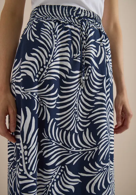 Donkerblauwe rok met wit bladerenpatroon, elastische taille en zijzakken, gecombineerd met een wit hemdje.