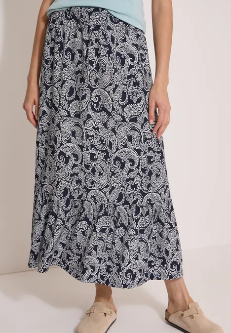 Lange, fließende Maxirock mit Paisley-Muster in Blau-Weiß, kombiniert mit lockeren Sandalen.