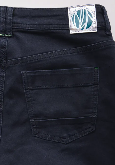 Gros plan sur un jean foncé avec poche arrière et étiquette blanche.