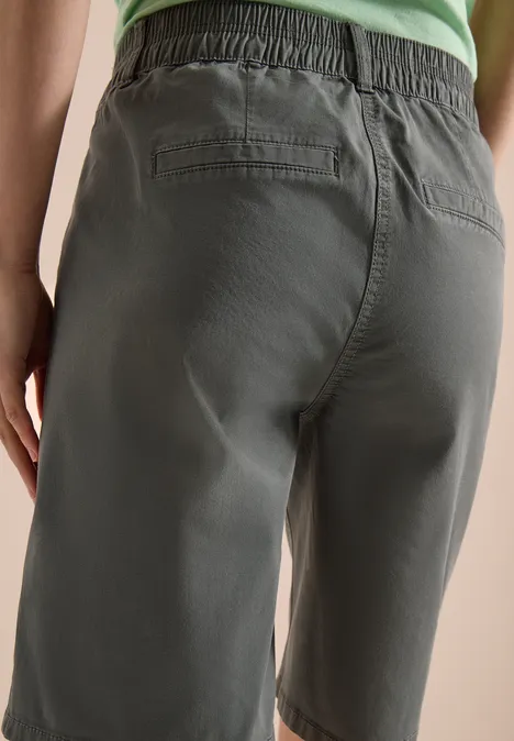 Achteraanzicht van een persoon in olijfgroene bermudashorts en groen topje.