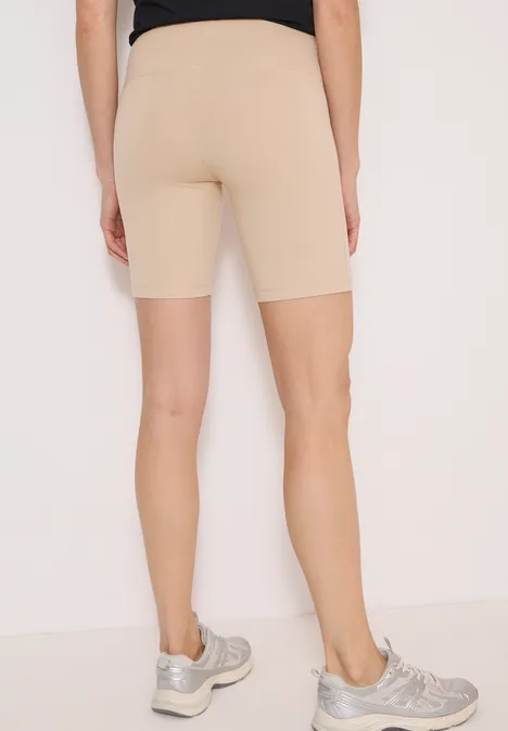 Person von hinten mit hautfarbenen Radlerhosen und silbernen Sportschuhen vor hellem Hintergrund.