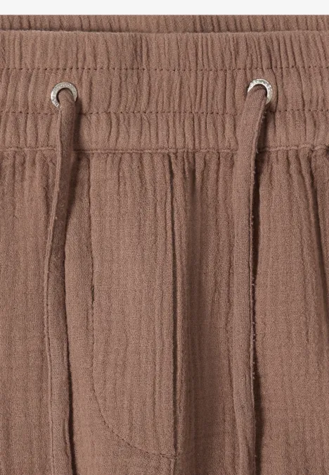 Nahaufnahme eines braunen, strukturierten Hosenbunds mit Gummizug und Kordelzug