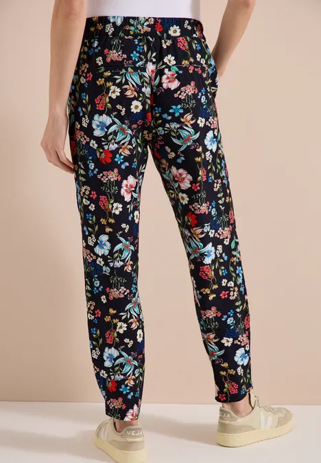 Hose mit schwarzem Blumenmuster an einem stehenden Modell.