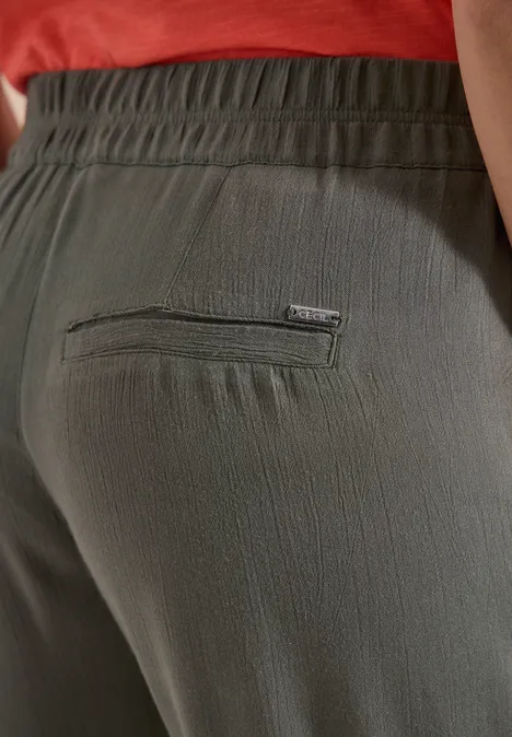 Close-up van olijfgroene, licht gestructureerde, elastische broek met achterzak.