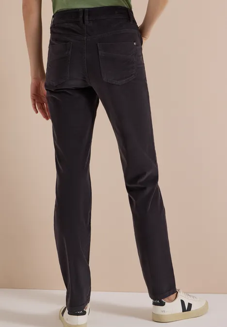 Pantalon gris foncé à jambes droites, vue de dos sur un porteur avec baskets blanches.