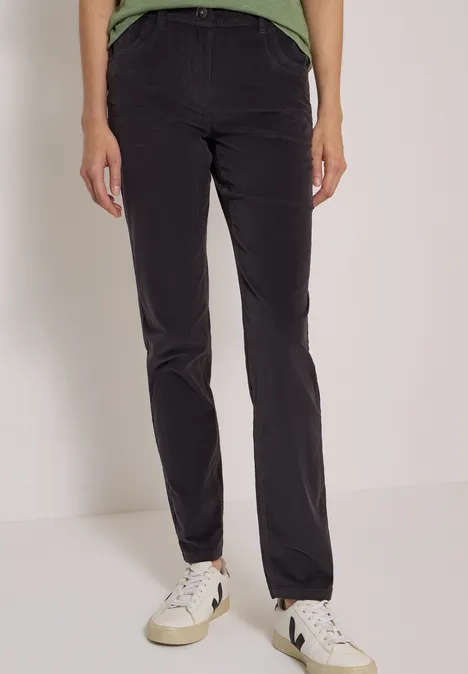 Pantalon noir et baskets blanches portés par un mannequin, photo prise sur fond clair.