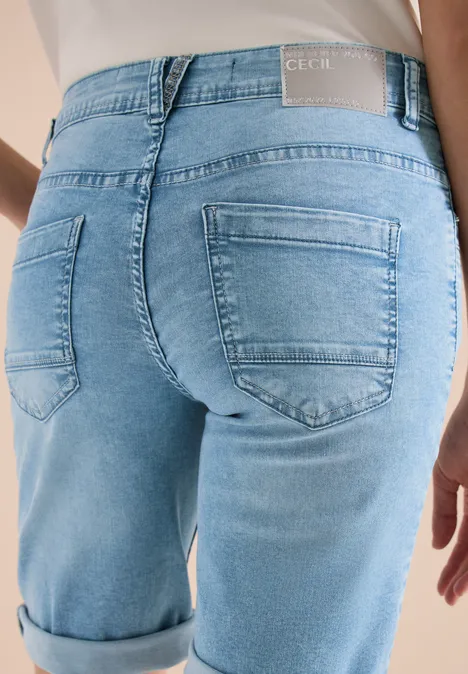 Nahaufnahme vom Gesäß einer Person in hochgekrempelten, hellblauen Jeanshosen.