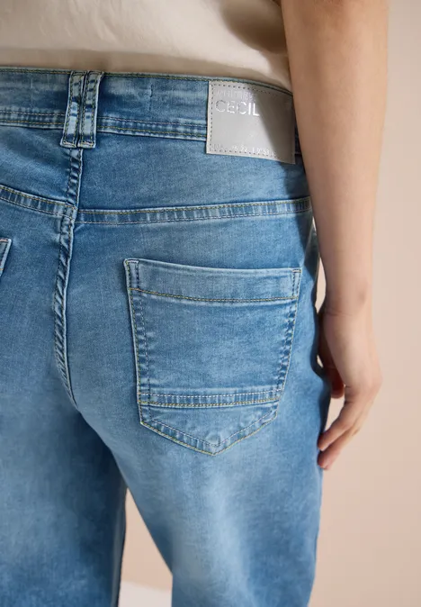 Achteraanzicht van een persoon in lichtblauwe spijkerbroek met zichtbare achterzak en label.