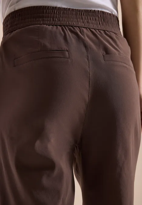 Achteraanzicht van een persoon met een bruine broek en wit shirt.