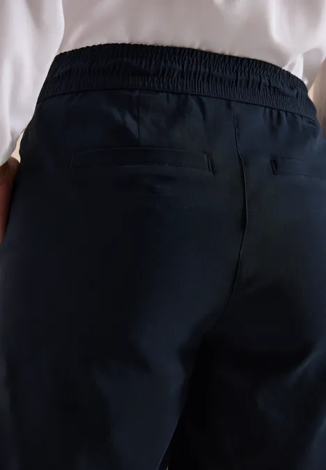 Straight Legs shorts in een Loose Fit universal blue Achteraanzicht van een persoon in donkerblauwe, elastische vrijetijdsbroek met handen in de zakken.