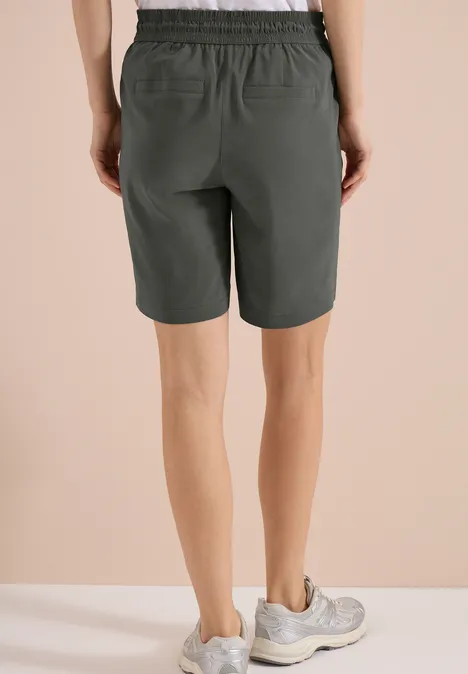 Straight Legs shorts in een Loose Fit clear khaki Achteraanzicht van iemand in knielange kaki short met witte sportschoenen