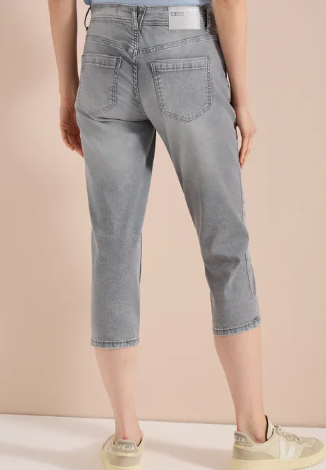 3/4 Slim Leg Jeans im Casual Fit mid grey used wash Person von hinten in grauen, knielangen Jeans und hellen Sneakern vor hellem Hintergrund.