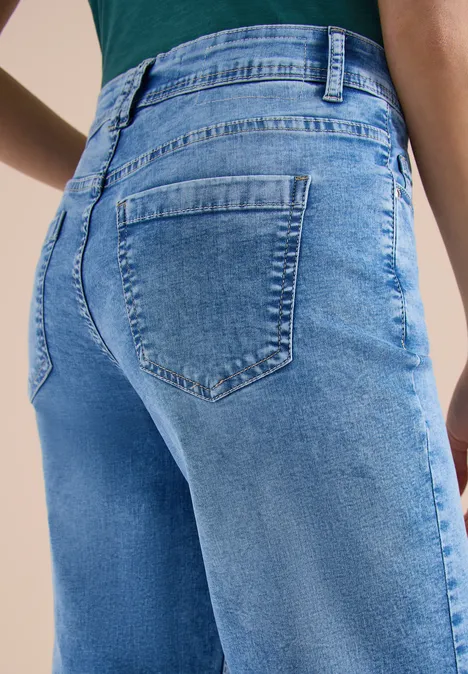 Een persoon draagt een strakke blauwe jeans, close-up van de achterkant en zakken.