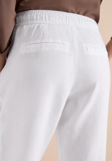 Rückansicht einer Person in weißen Stoffhosen mit elastischem Bund und zwei Gesäßtaschen.