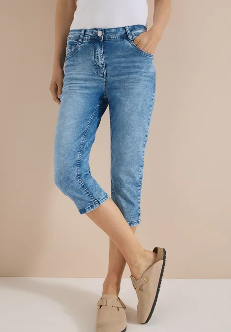 Eine Person trägt hellblaue Capri-Jeans und beige Mokassins.