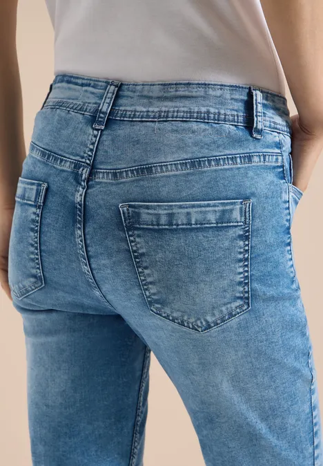 Frau trägt hellblaue Jeans mit sichtbaren Gesäßstaschen und weißem Shirt.