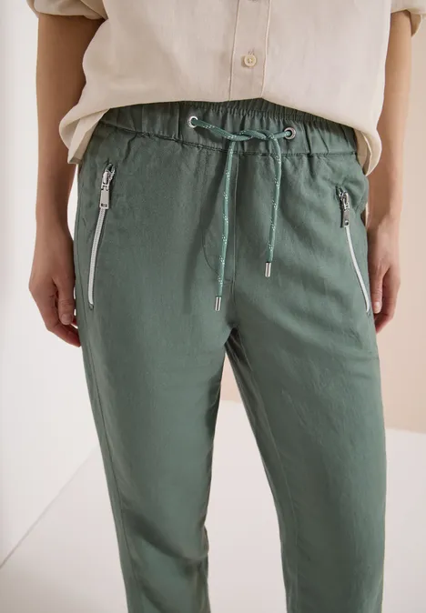 Modische hellgrüne Freizeithose mit elastischem Bund, Kordelzug und seitlichen Reißverschlusstaschen.