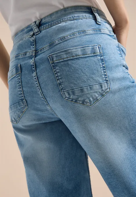 Nahaufnahme einer Person von hinten in blauen Jeans und weißem Oberteil.