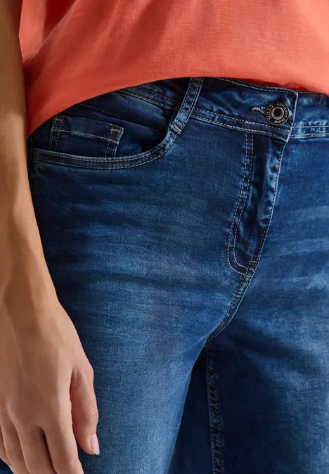 Wide Leg 3/4 Jeans im Loose Fit mid blue used wash Eine Person trägt ein rotes Shirt und dunkle Jeans, die Hand liegt entspannt neben dem Oberschenkel.