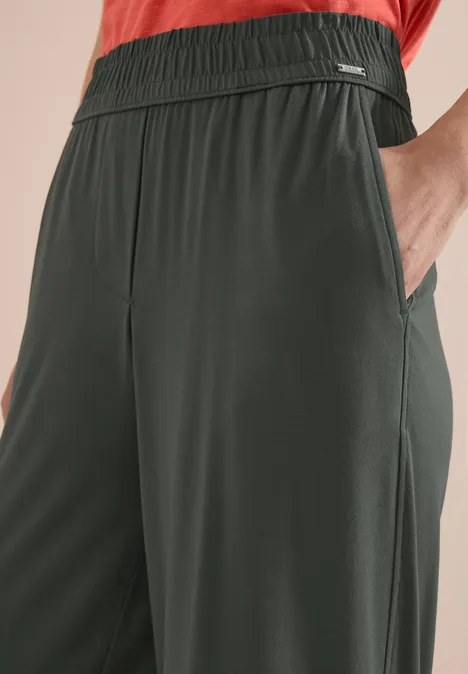 Dunkelgrüne, locker sitzende Hose mit Gummibund und seitlichen Taschen.