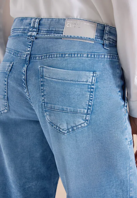 Rückansicht einer Person in hellblauen Jeans und weißem Oberteil.